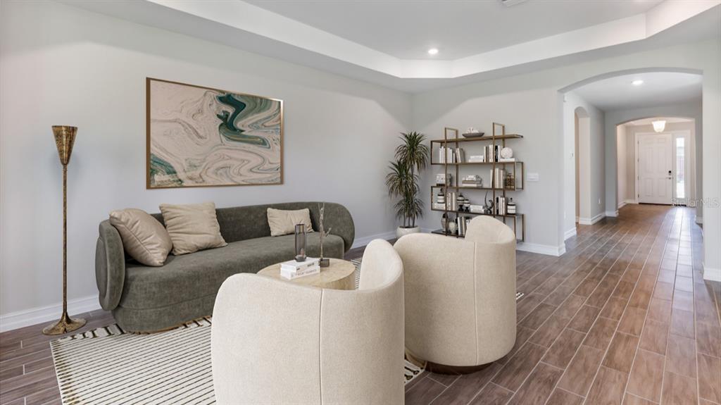A living room features a curved sofa, two armchairs, a bookshelf, and tile flooring — 12736 SEAGRASS DRIVE, PUNTA GORDA, FL