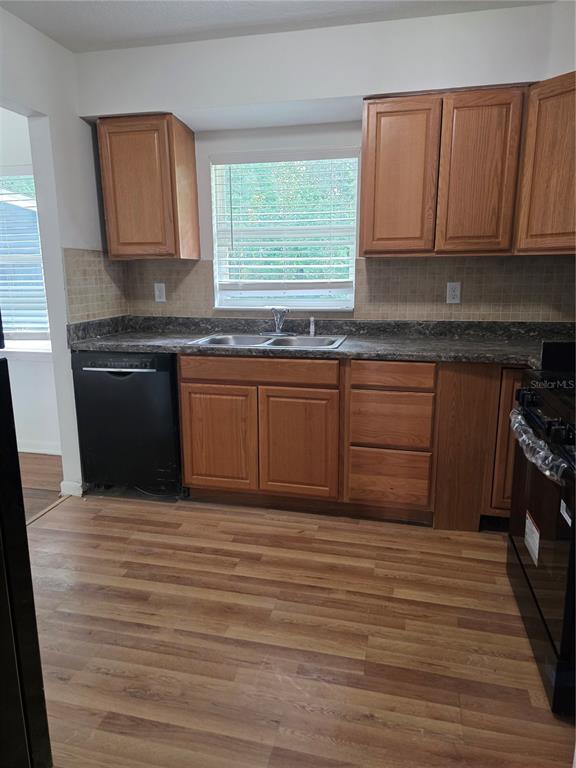 A kitchen features wood cabinets, a dark countertop, a black dishwasher, and wood-look flooring — 507 NE 21ST TERRACE, OCALA, FL