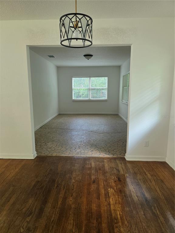 A room with hardwood floors opens into a secondary space featuring stone-patterned tile flooring — 507 NE 21ST TERRACE, OCALA, FL
