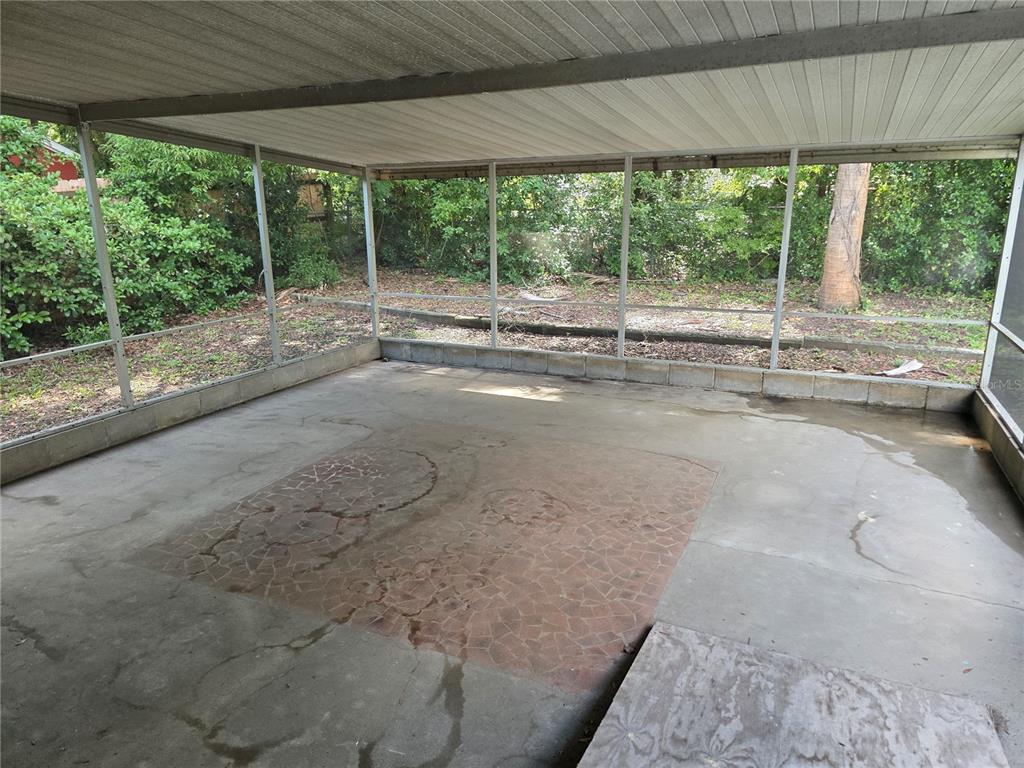 A screened-in concrete patio features a central decorative tiled area and views of trees — 507 NE 21ST TERRACE, OCALA, FL