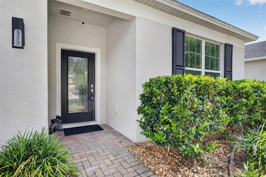 The front entrance of a house features a paved walkway, a dark door, and landscaping — 12637 OLD PLANTATION LANE, ORLANDO, FL