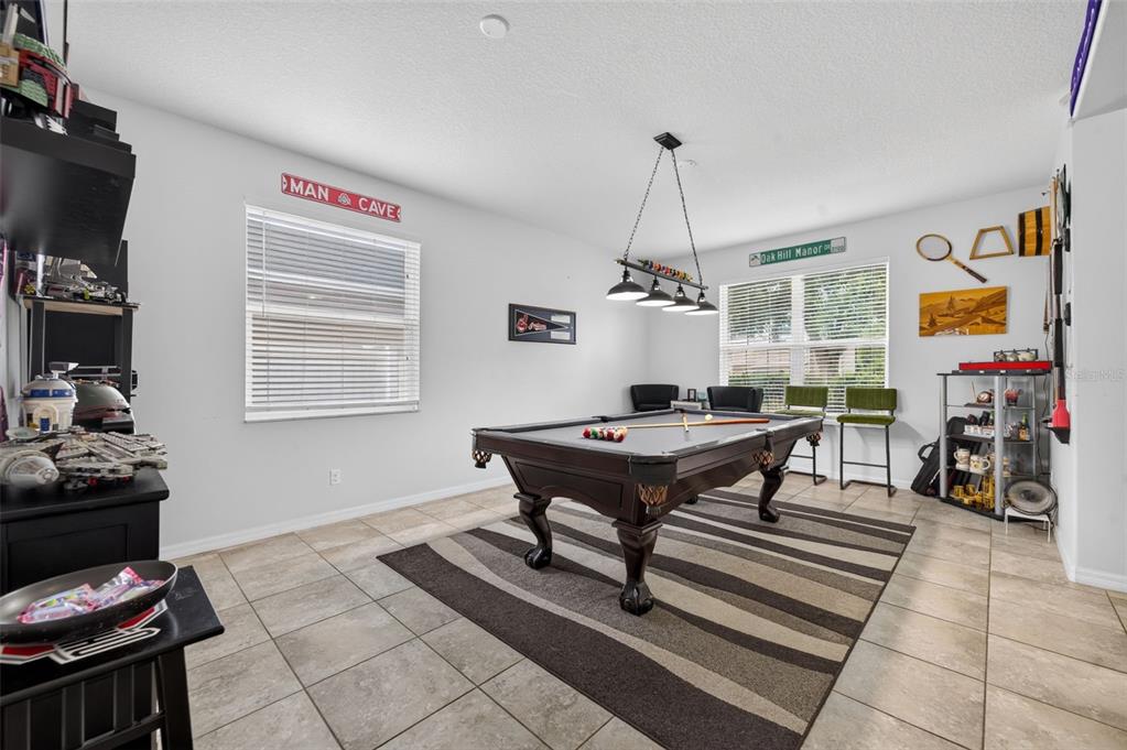 A game room features a pool table on a striped rug, tile flooring, and windows — 12637 OLD PLANTATION LANE, ORLANDO, FL