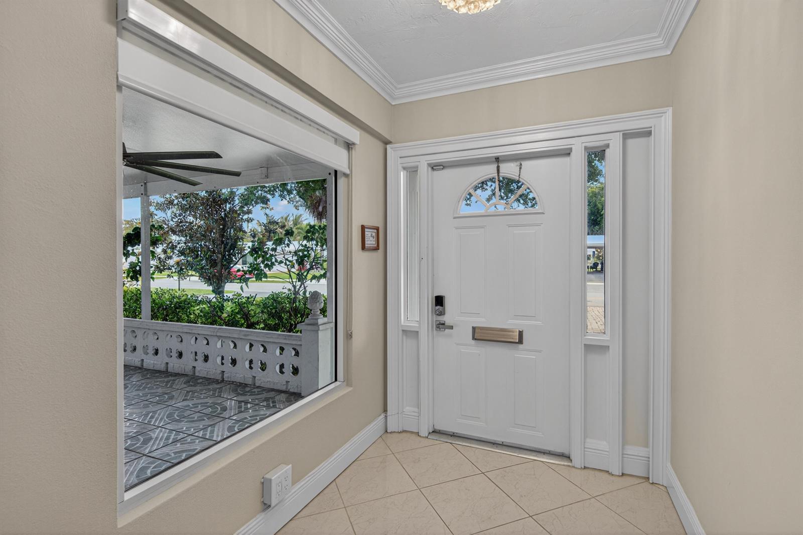 An entryway with beige tile floors, a white front door, and a large windowed wall — 391 Leisure Boulevard, Pompano Beach FL 33064, POMPANO BEACH, FL