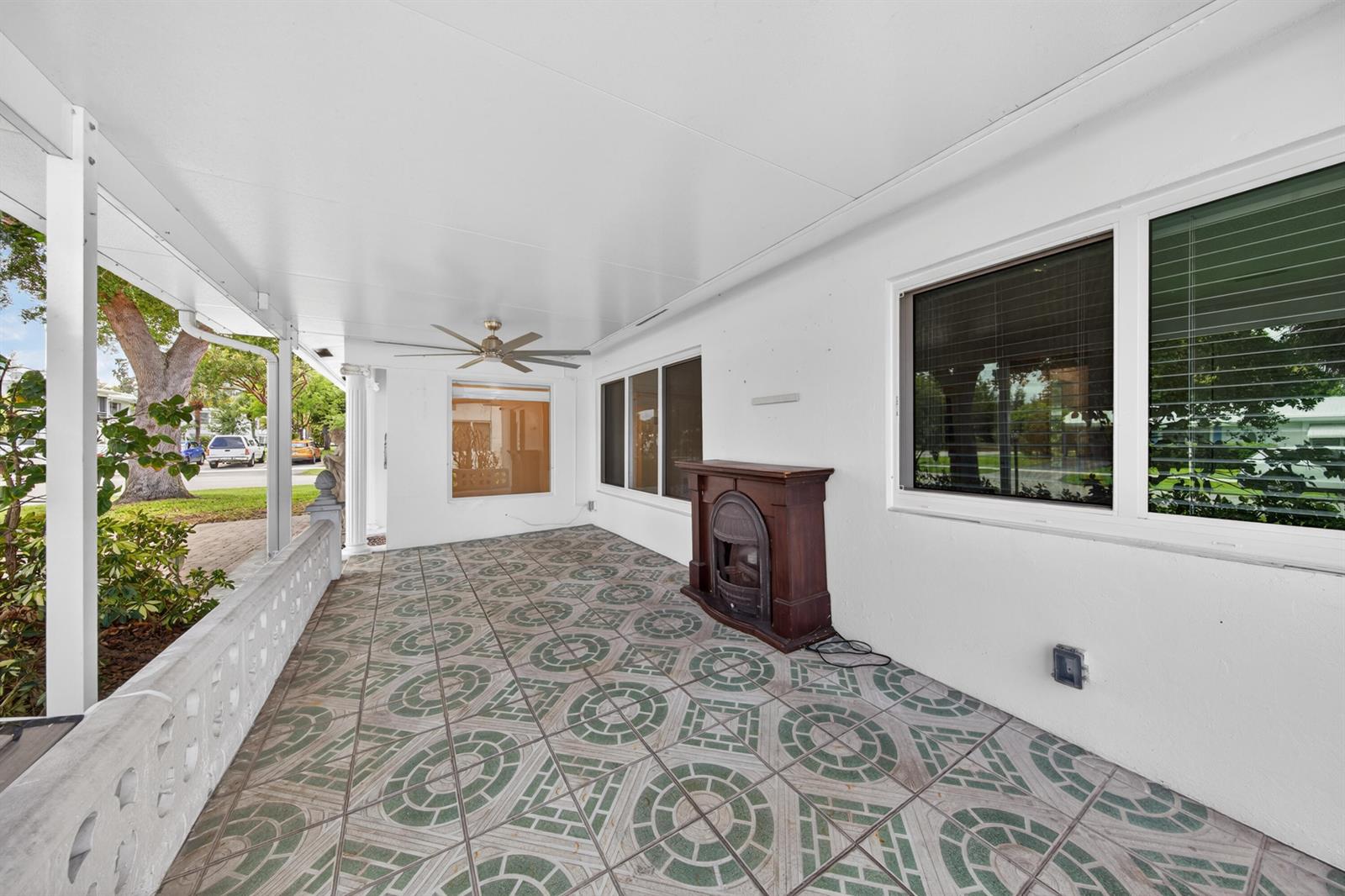 A covered outdoor patio features patterned tile flooring, a ceiling fan, and a portable fireplace — 391 Leisure Boulevard, Pompano Beach FL 33064, POMPANO BEACH, FL