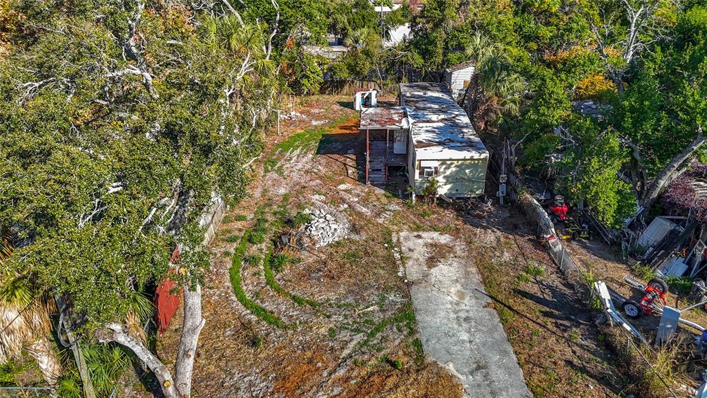 An aerial view shows a weathered mobile home on a lot with trees and debris — 7135 ELIZABETH AVENUE, HUDSON, FL