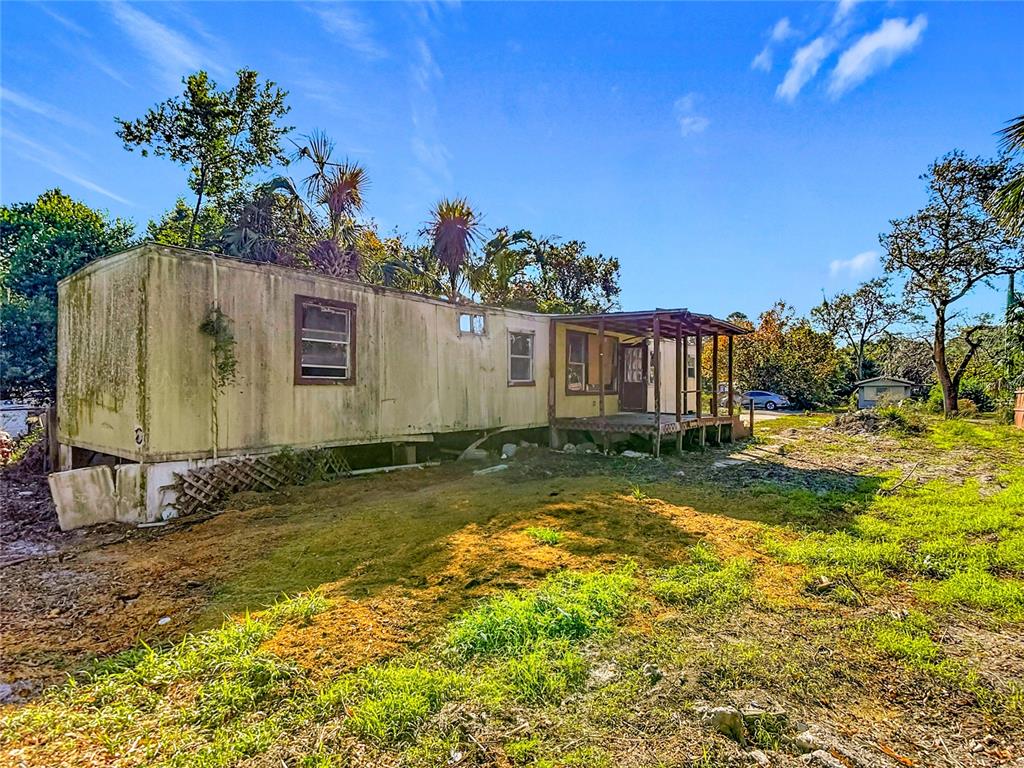 A weathered mobile home with a wooden porch sits on a grassy, partially cleared lot — 7135 ELIZABETH AVENUE, HUDSON, FL