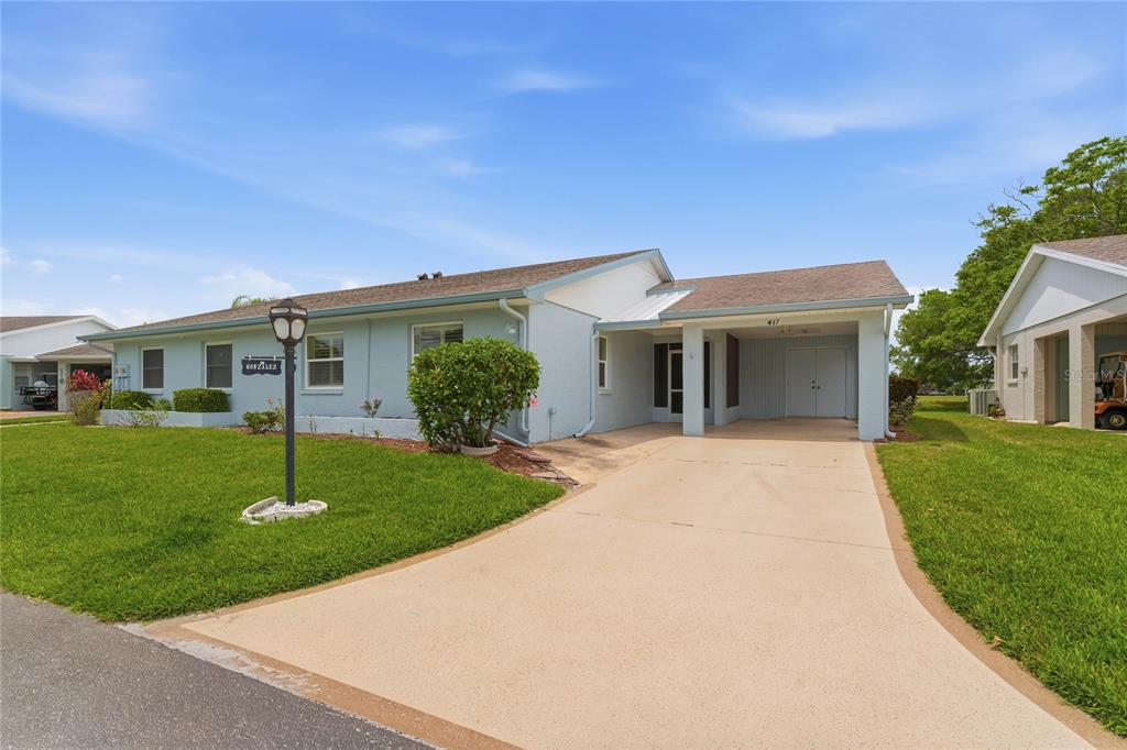 A light blue single-story house with a concrete driveway and a covered entryway at dusk — 417 GLADSTONE PLACE, SUN CITY CENTER, FL