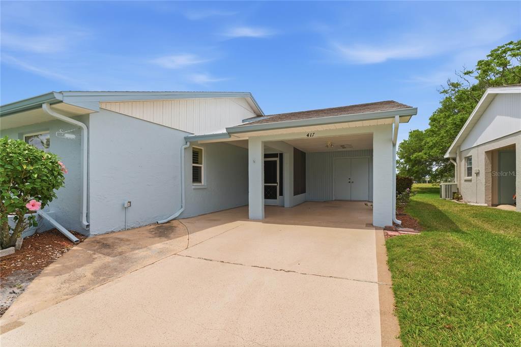 A light blue house features a covered carport and a concrete driveway — 417 GLADSTONE PLACE, SUN CITY CENTER, FL