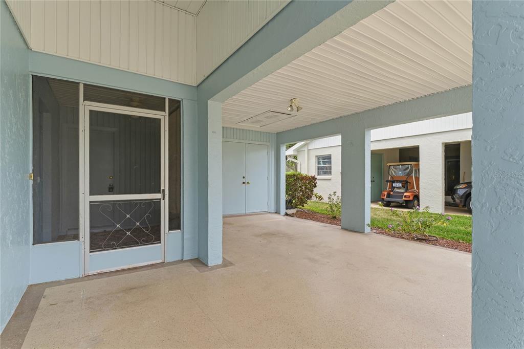 A covered patio area features a screened door, light blue walls, and a concrete floor — 417 GLADSTONE PLACE, SUN CITY CENTER, FL