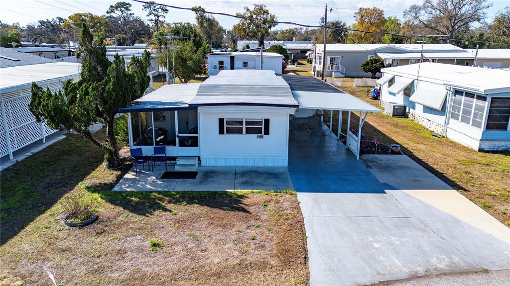 An elevated exterior view of a mobile home with a carport and a screened porch — 37332 SANDRA AVENUE, ZEPHYRHILLS, FL