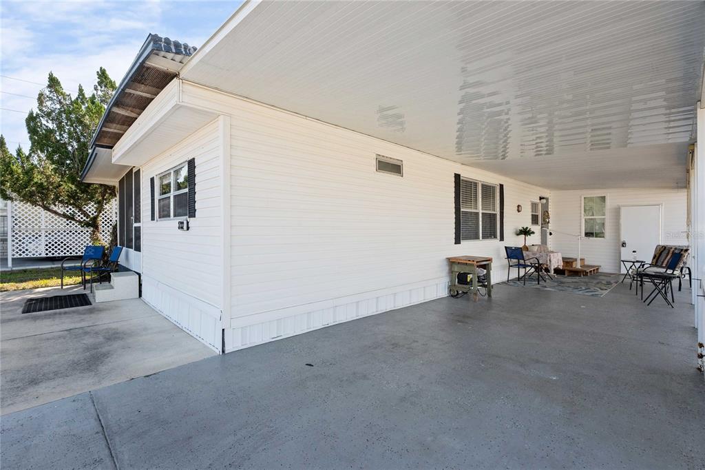 A wide concrete carport extends along the side of a white mobile home — 37332 SANDRA AVENUE, ZEPHYRHILLS, FL