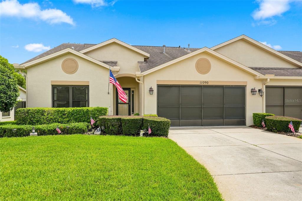 A single-story house with a beige stucco exterior, a garage, and a manicured front lawn — 11090 CHERRYWOOD COURT, SPRING HILL, FL