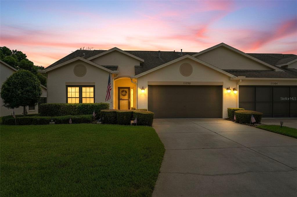 A single-story house with a two-car garage at sunset with a manicured lawn — 11090 CHERRYWOOD COURT, SPRING HILL, FL