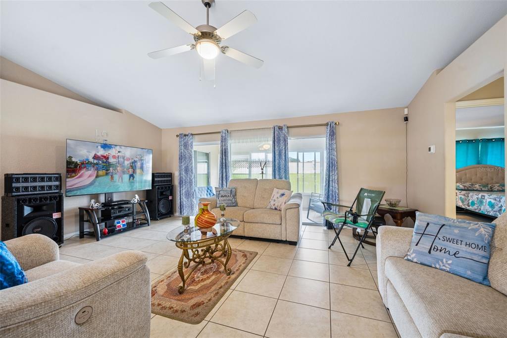 A living room features tile flooring, a ceiling fan, a television, and beige furniture — 140 MORNING GLORY CIRCLE, WINTER HAVEN, FL