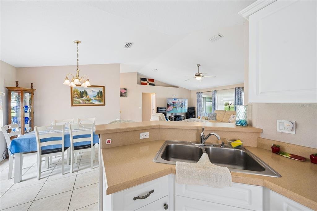 A kitchen sink and countertop overlook an open-concept dining area and living room — 140 MORNING GLORY CIRCLE, WINTER HAVEN, FL
