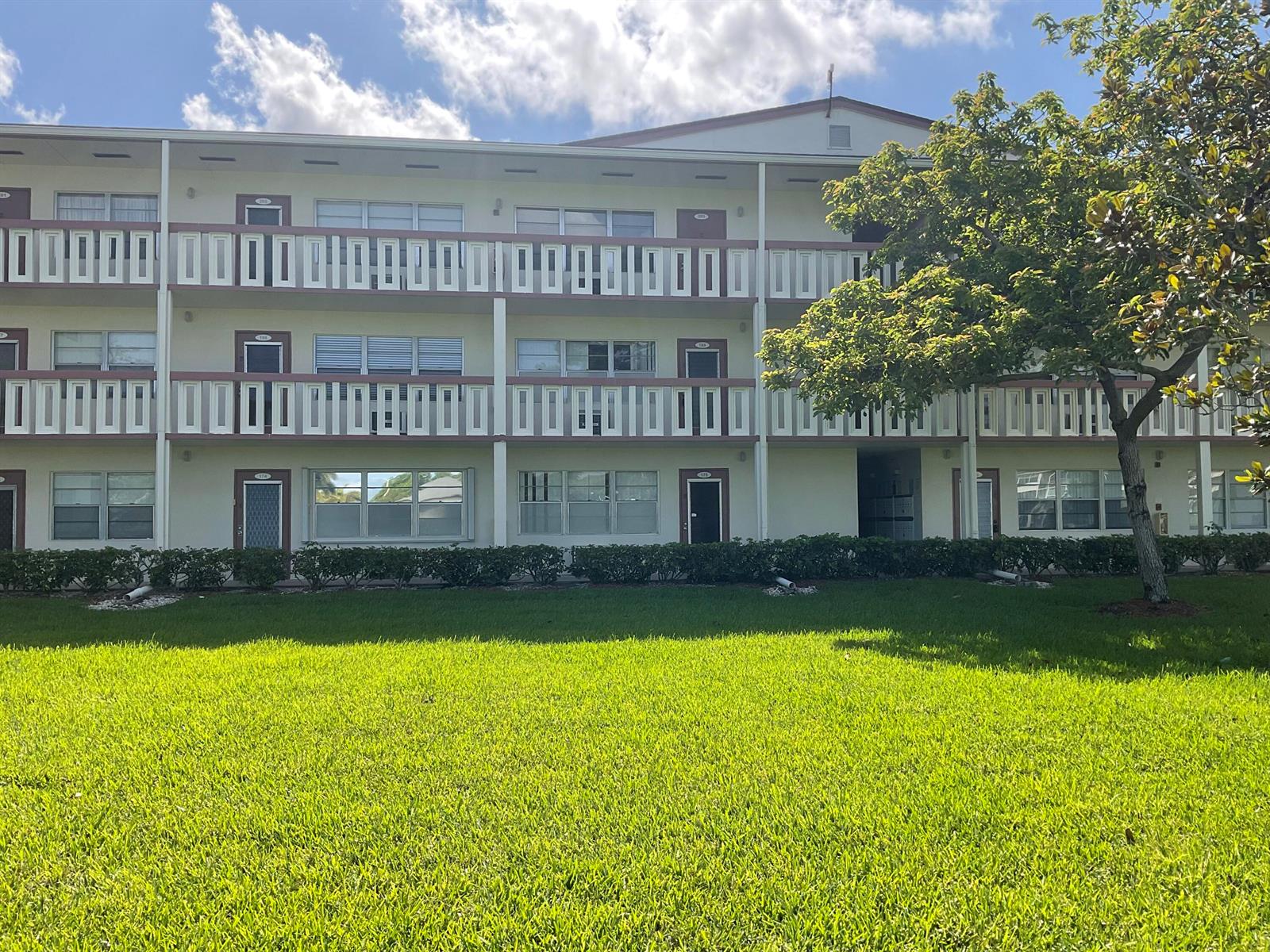 A three-story apartment building features exterior walkways, balconies with decorative railings, and a front lawn — 189 E Preston Way, Boca Raton FL 33434, BOCA RATON, FL