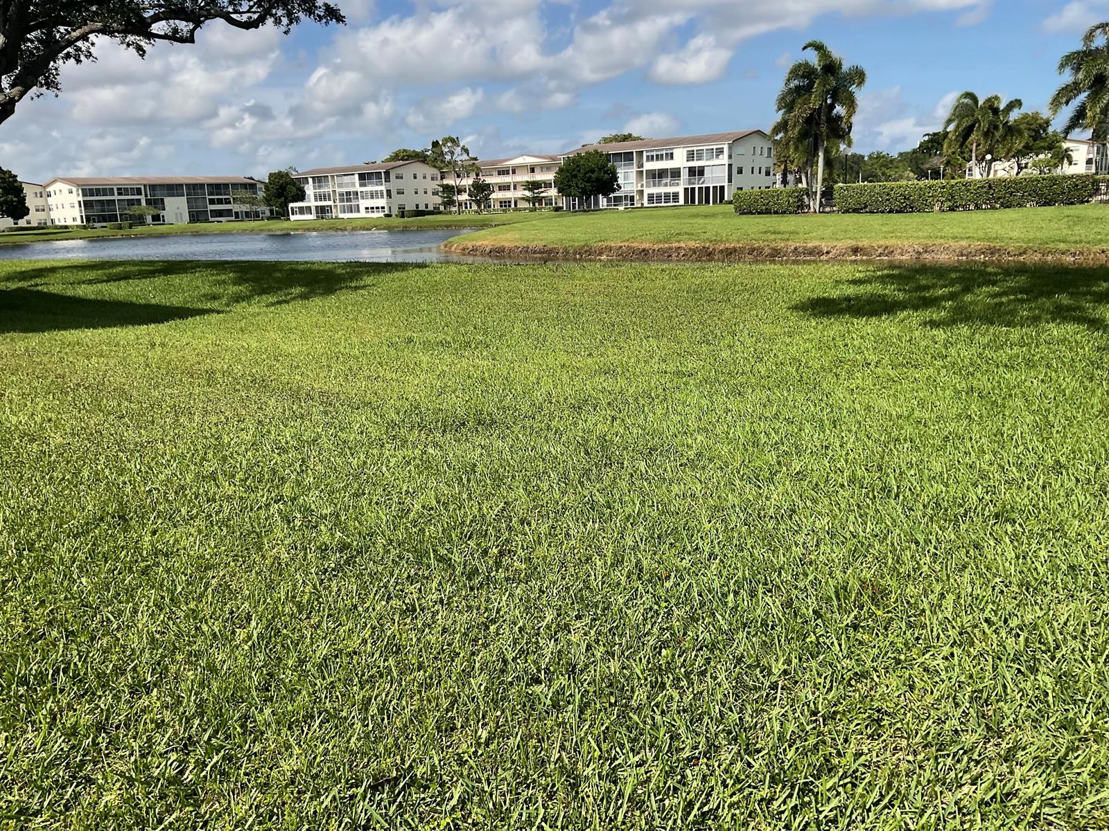 A grassy lawn leads to a pond in front of multi-story apartment buildings — 189 E Preston Way, Boca Raton FL 33434, BOCA RATON, FL