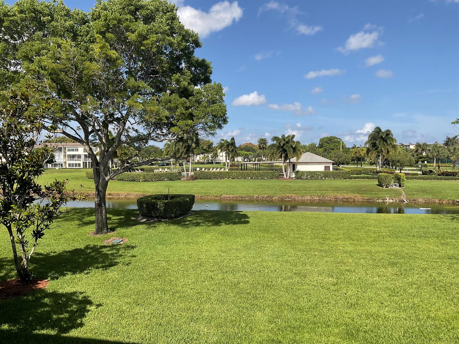 A grassy lawn overlooks a narrow canal with a small building and palm trees beyond — 189 E Preston Way, Boca Raton FL 33434, BOCA RATON, FL