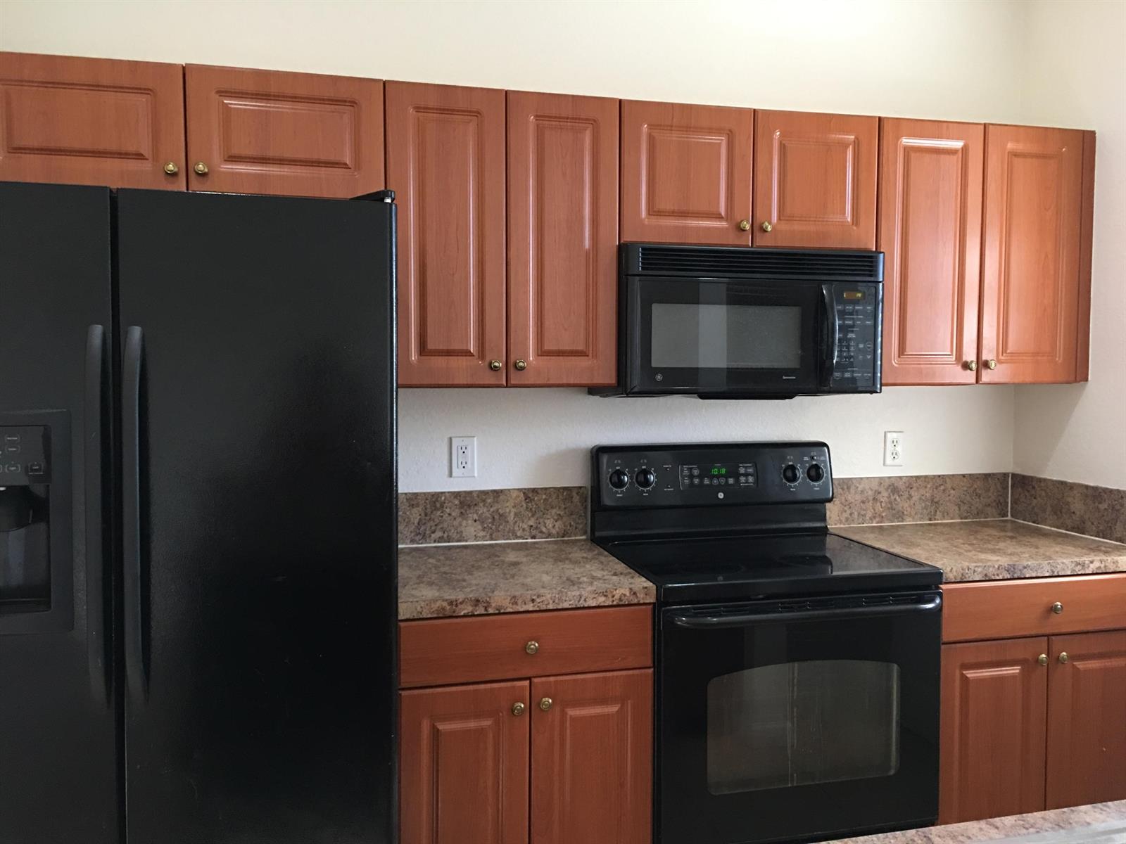 A kitchen features wood cabinets, black appliances, and a brown speckled laminate countertop — 1213 Abaco Lane, West Palm Beach FL 33404, WEST PALM BEACH, FL