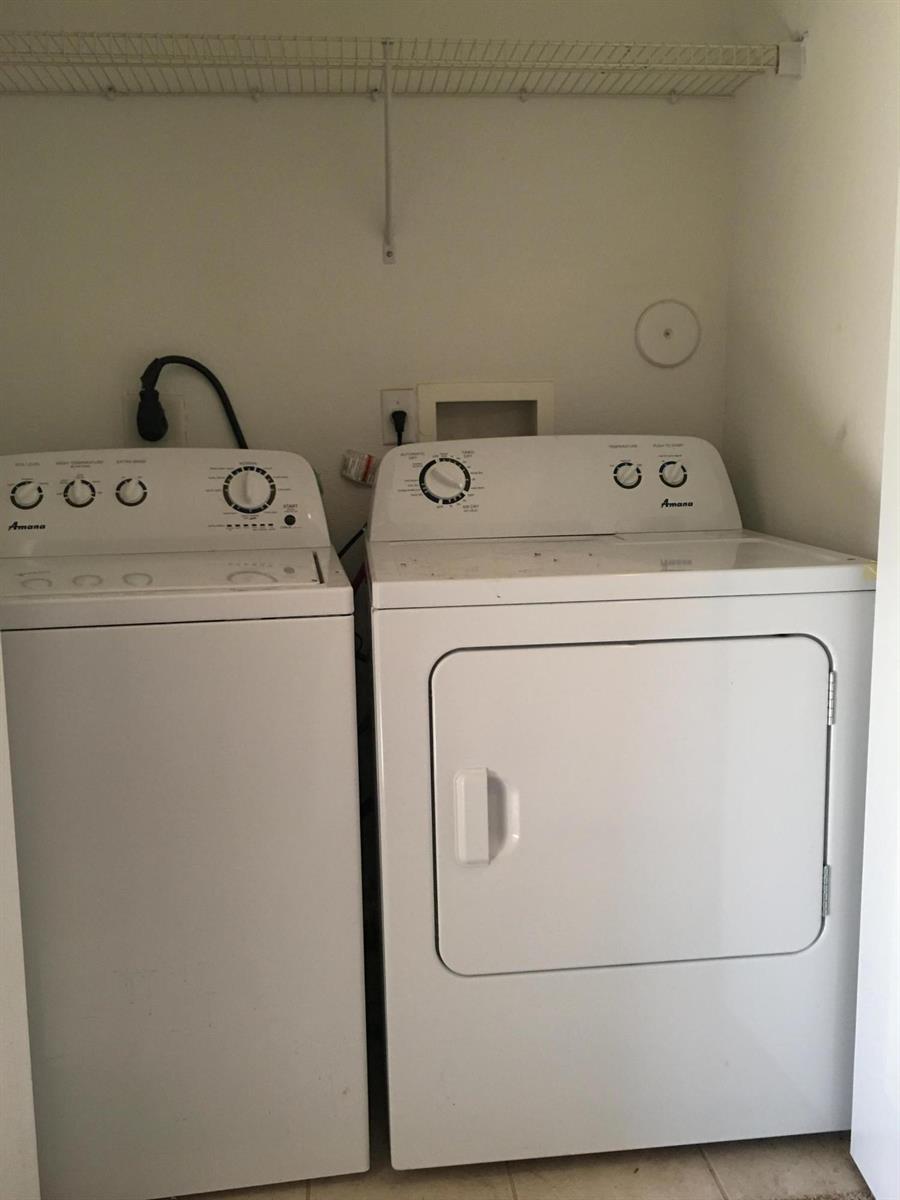 A laundry closet contains a white Amana top-load washer and a matching front-load dryer — 1213 Abaco Lane, West Palm Beach FL 33404, WEST PALM BEACH, FL