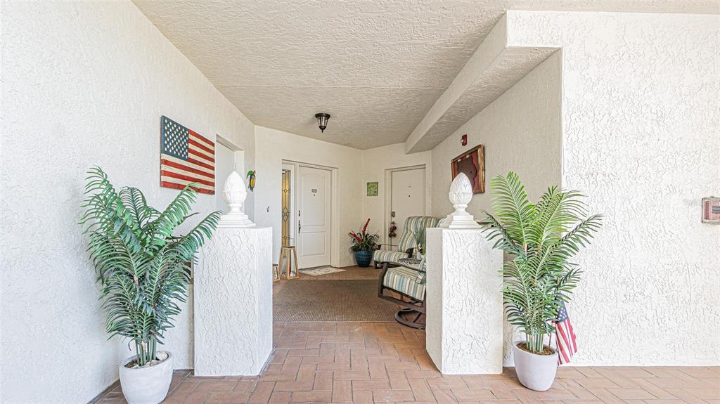 A covered entryway features tiled flooring, two potted plants, and a white front door — 200 121ST AVENUE UNIT 304, TREASURE ISLAND, FL