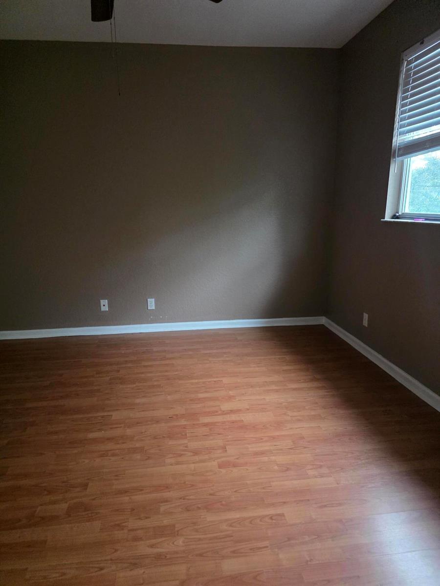 An empty room with brown walls, wood-look flooring, and a window with white blinds — 2866 S Oasis Drive, Boynton Beach FL 33426, BOYNTON BEACH, FL