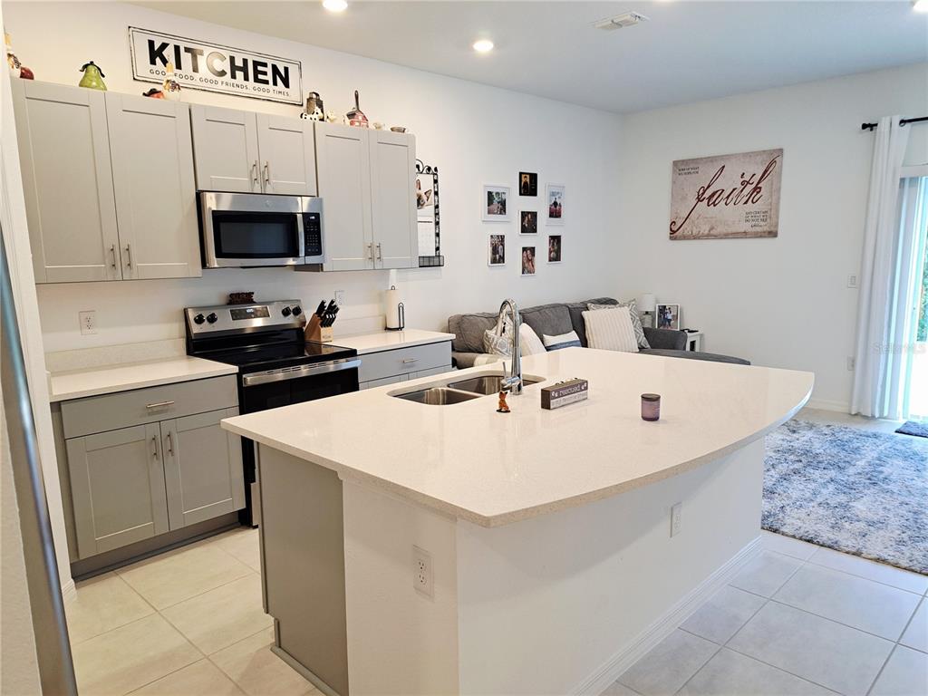 A kitchen with light gray cabinets, a white island, and an adjacent living area — 2991 CANARY AVENUE, DAVENPORT, FL