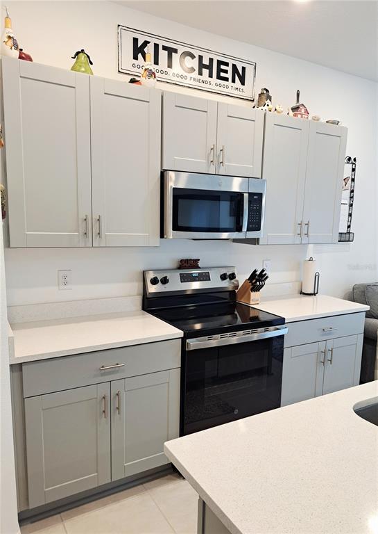 A kitchen features light gray cabinets, white countertops, and stainless steel appliances — 2991 CANARY AVENUE, DAVENPORT, FL