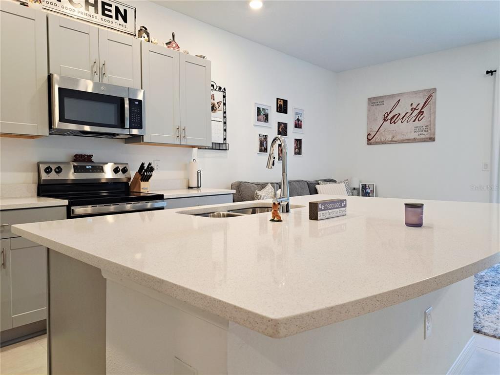A kitchen island with a light-colored countertop sits in front of gray cabinets and appliances — 2991 CANARY AVENUE, DAVENPORT, FL