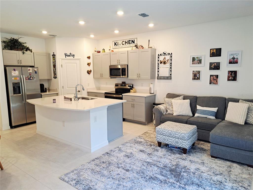 An open-concept kitchen with light gray cabinets, a white island, and an adjacent living area — 2991 CANARY AVENUE, DAVENPORT, FL