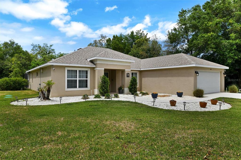 A single-story tan stucco house with a white garage and a landscaped front yard — 4255 RACHEL BOULEVARD, SPRING HILL, FL