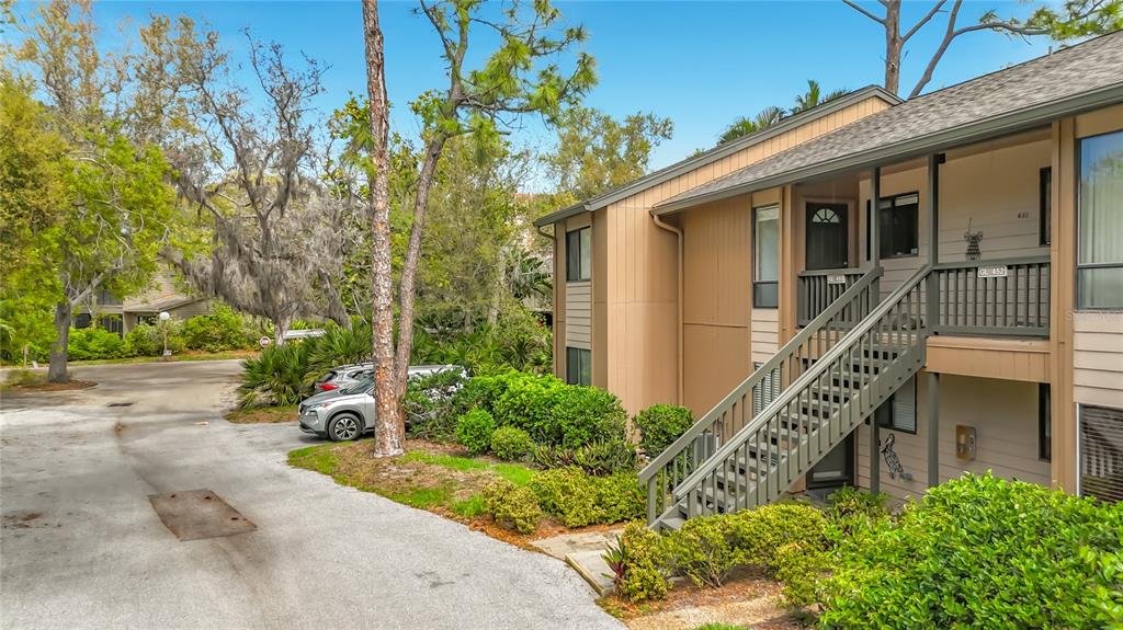 An exterior view of a two-story apartment building with wooden siding and an outdoor staircase — 1707 PELICAN COVE ROAD UNIT GL351, SARASOTA, FL