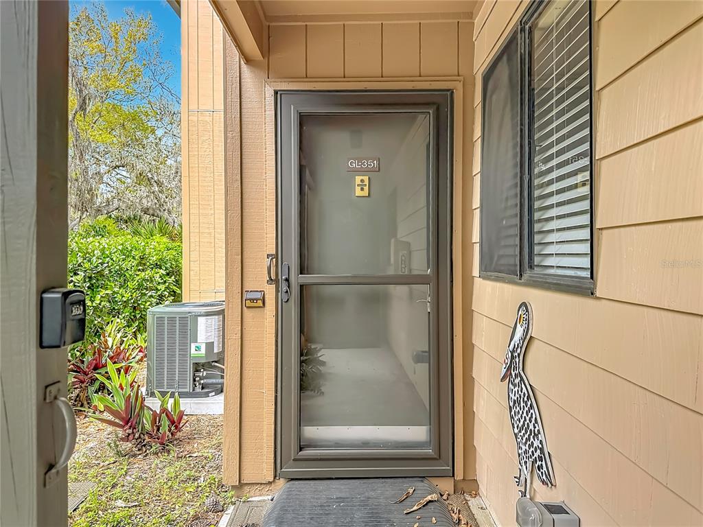 A view of a residential entryway with a glass storm door and a pelican decoration — 1707 PELICAN COVE ROAD UNIT GL351, SARASOTA, FL