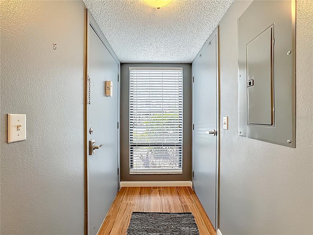 A narrow entryway features wood-look tile flooring, a window with blinds, and a circuit breaker panel — 1707 PELICAN COVE ROAD UNIT GL351, SARASOTA, FL