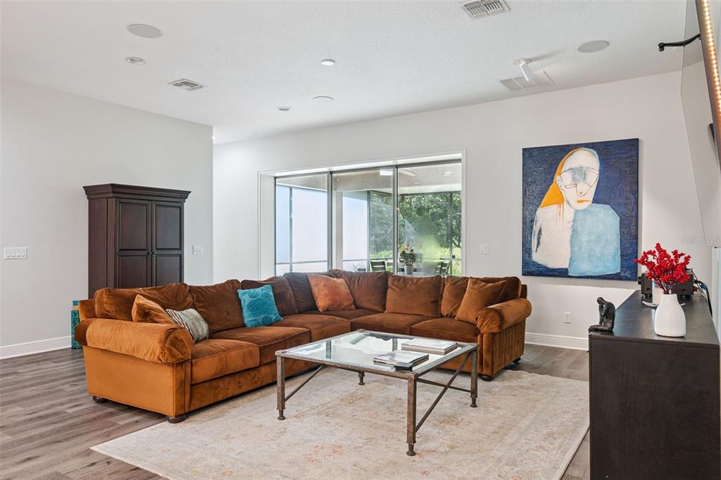 A living room features a brown sectional sofa, a glass coffee table, and abstract wall art — 14156 ALAFAYA OAK BEND, ORLANDO, FL