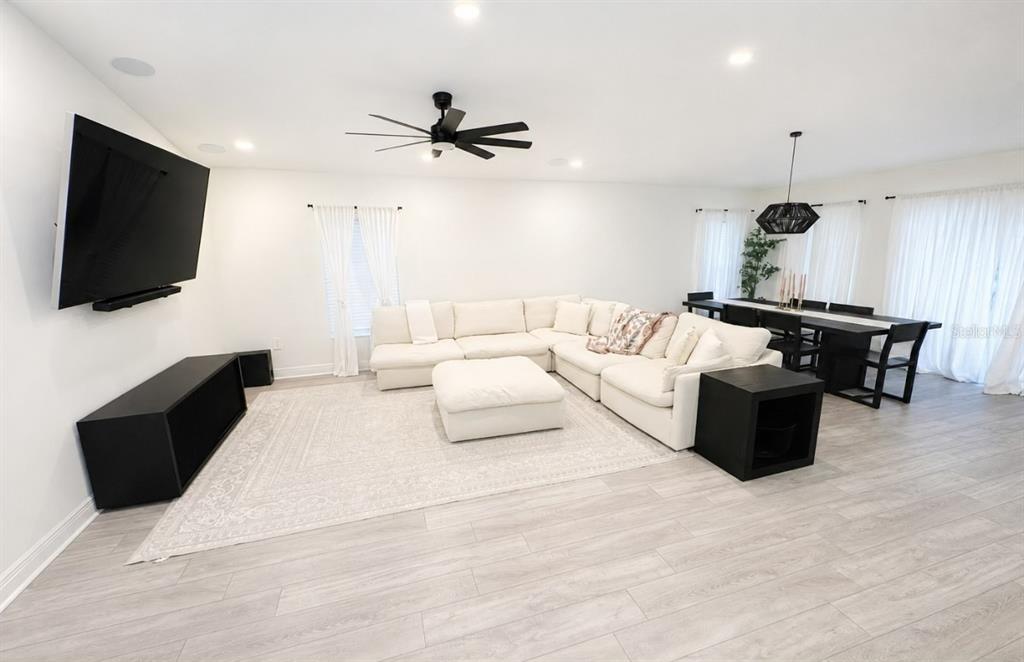 A living and dining room features white walls, light wood floors, and black furniture — 1378 PARK LEAH CIRCLE, APOPKA, FL