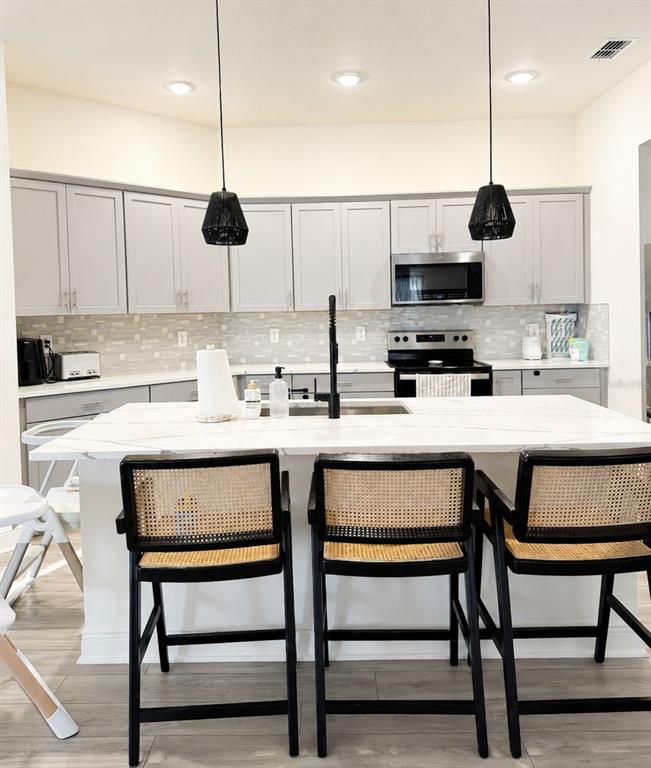 A kitchen features light gray cabinets, a white marble island, and three black cane stools — 1378 PARK LEAH CIRCLE, APOPKA, FL