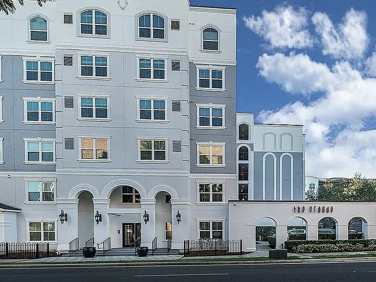 The exterior of a multi-story apartment building features light gray siding and arched entryway details — 304 E SOUTH STREET UNIT 2029, ORLANDO, FL