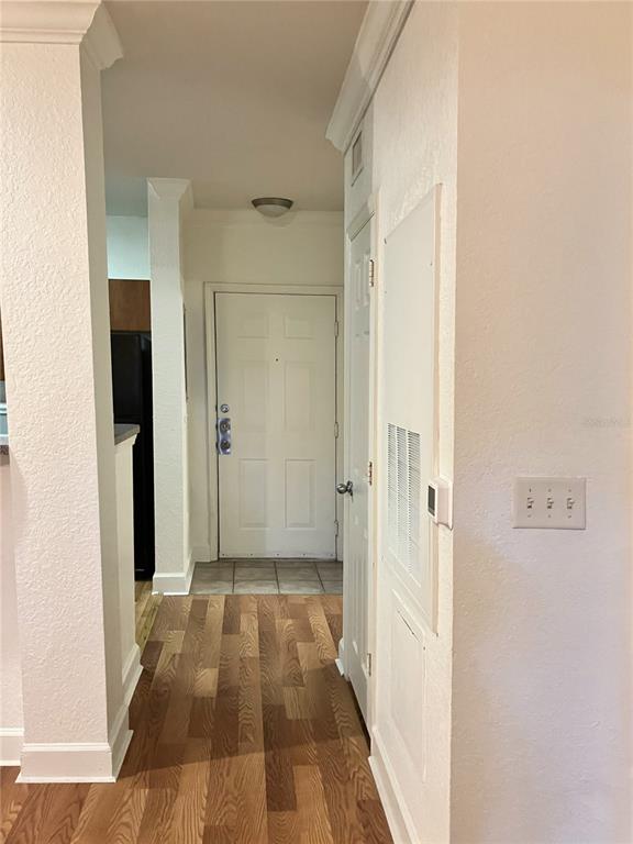 A hallway with wood-look flooring leads to a white front door and a utility closet — 304 E SOUTH STREET UNIT 2029, ORLANDO, FL
