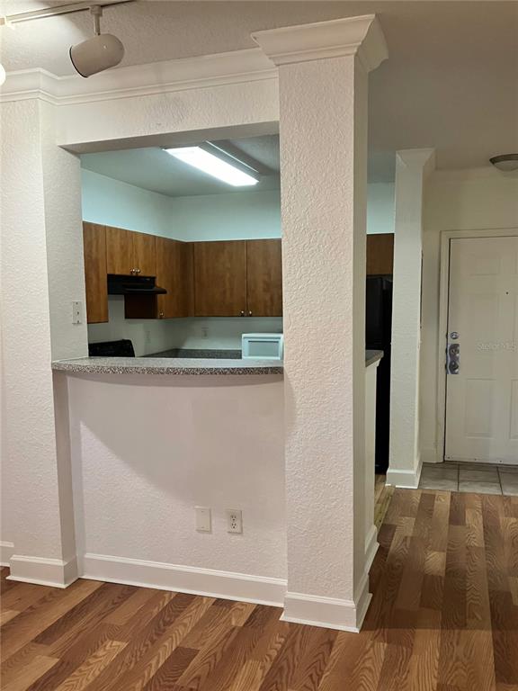 A kitchen with wood cabinets and a breakfast bar overlooks a room with wood flooring — 304 E SOUTH STREET UNIT 2029, ORLANDO, FL