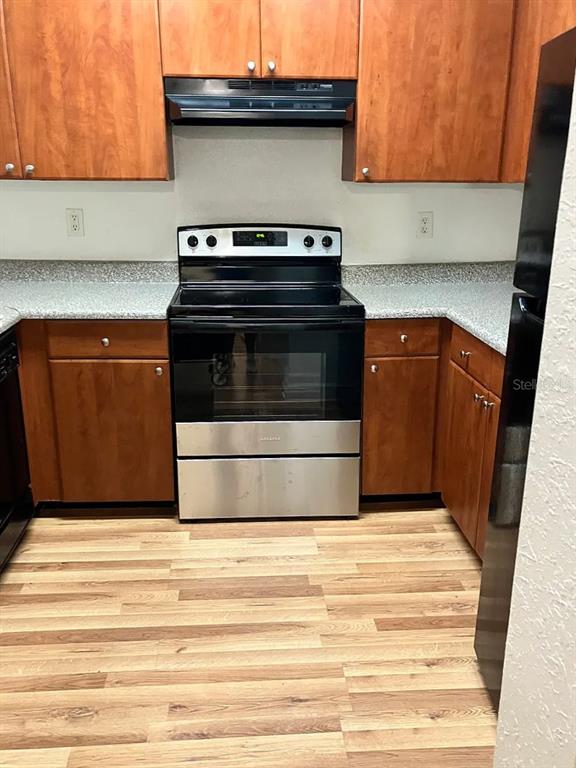 A kitchen features wood cabinets, a stainless steel stove, and light-colored countertops — 304 E SOUTH STREET UNIT 2029, ORLANDO, FL