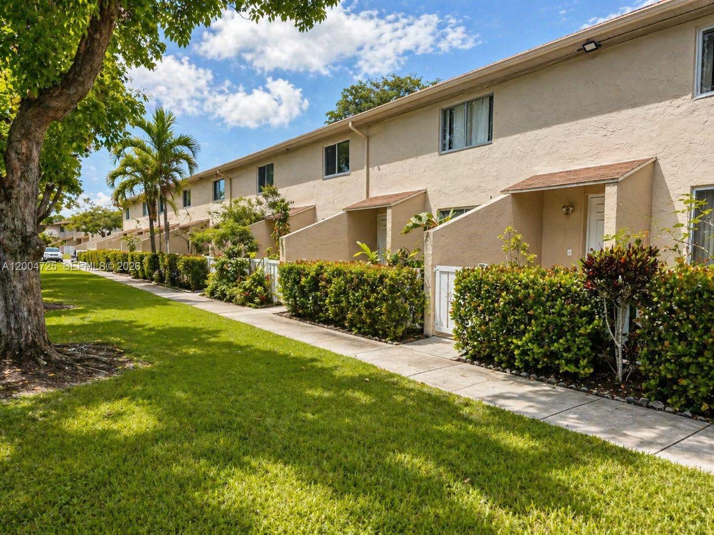 A row of tan townhouses with small private patios and landscaped hedges along a sidewalk — 1531 NW 80th Ave # I, Margate FL 33063, MARGATE, FL