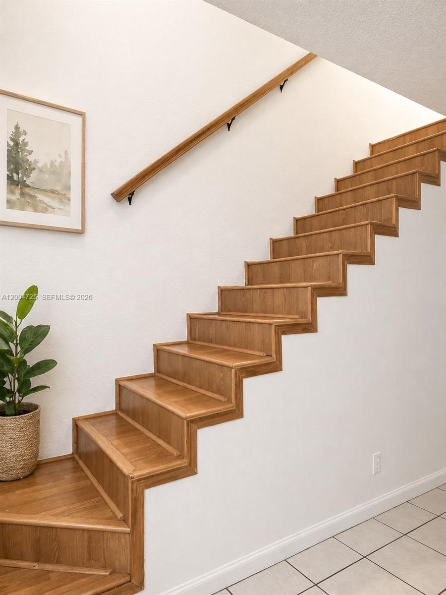 A wooden staircase with a matching handrail ascends along a white wall — 1531 NW 80th Ave # I, Margate FL 33063, MARGATE, FL