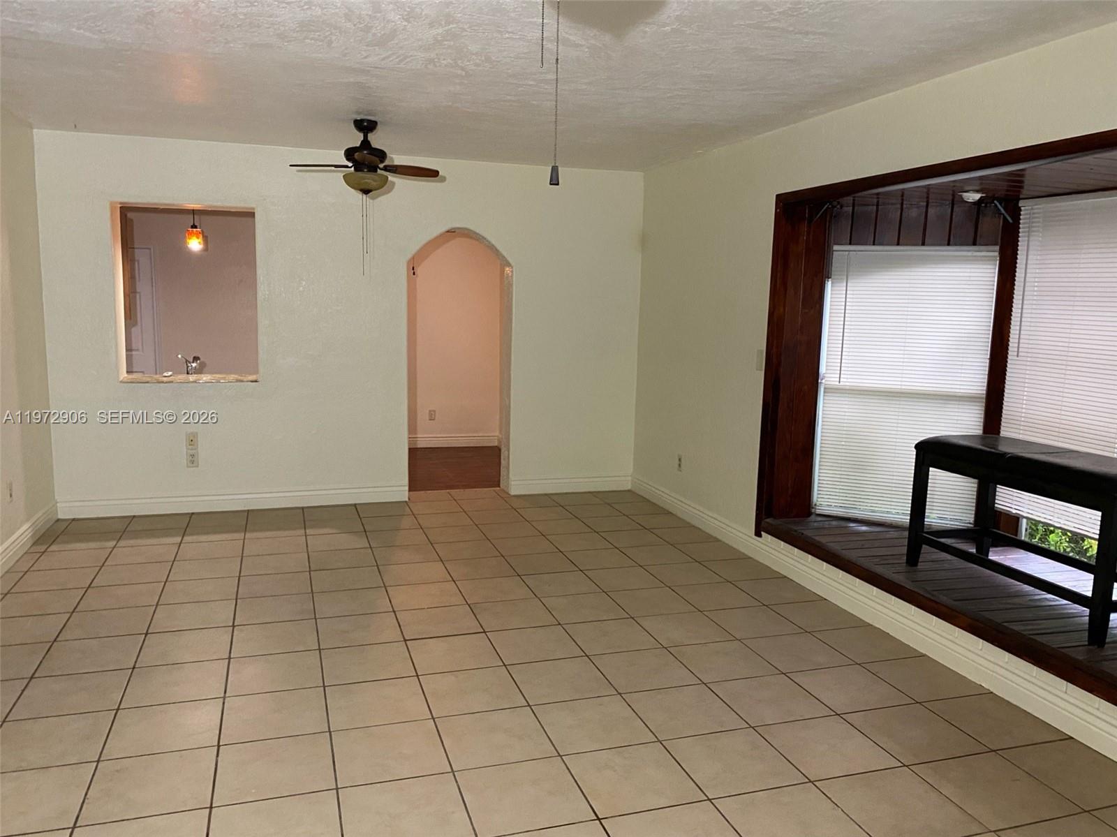 A room with beige tile flooring, an arched doorway, a ceiling fan, and a bay window — 1467 Renton St., Deltona FL 32725, DELTONA, FL