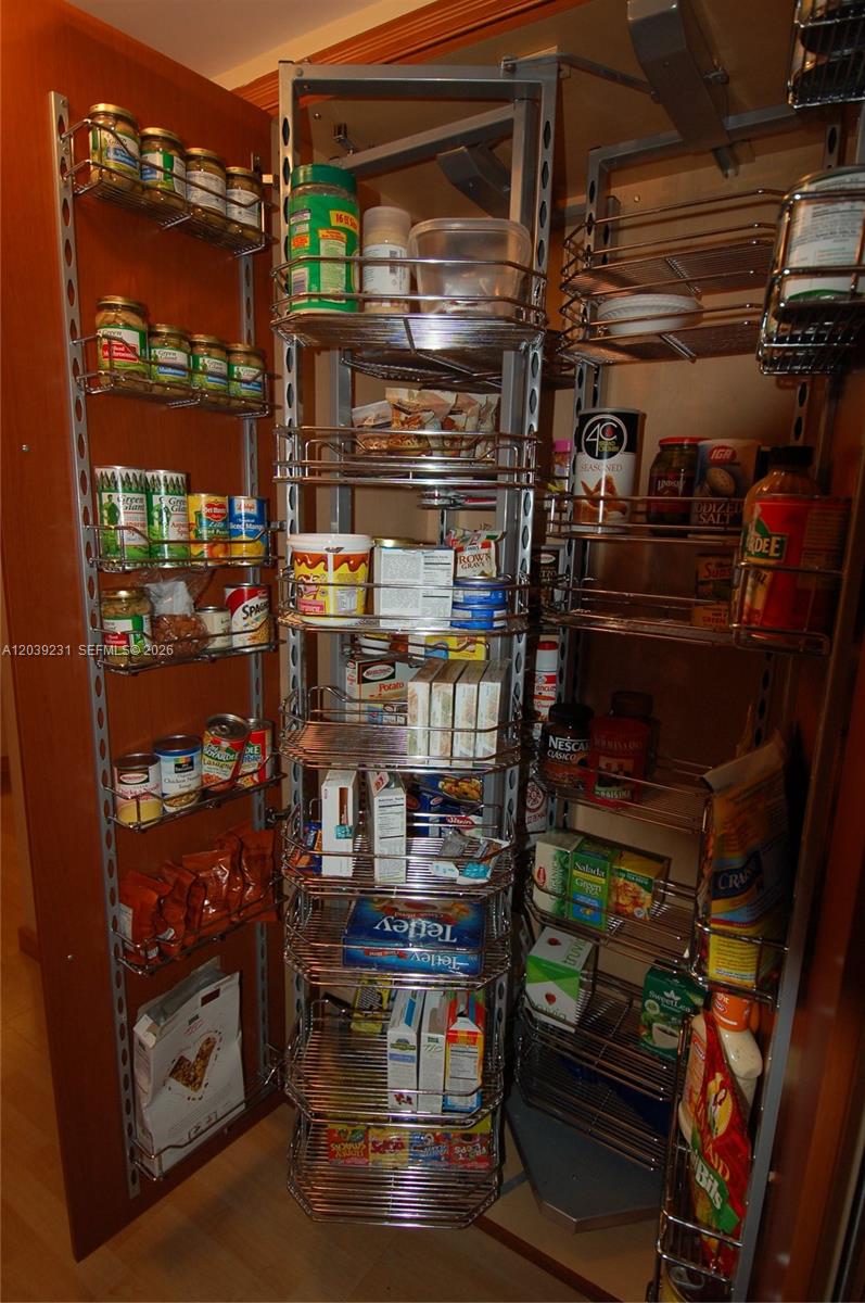 A tall, pull-out pantry cabinet is filled with various canned goods, boxes, and food items — 8877 Collins Ave # 507, Surfside FL 33154, SURFSIDE, FL
