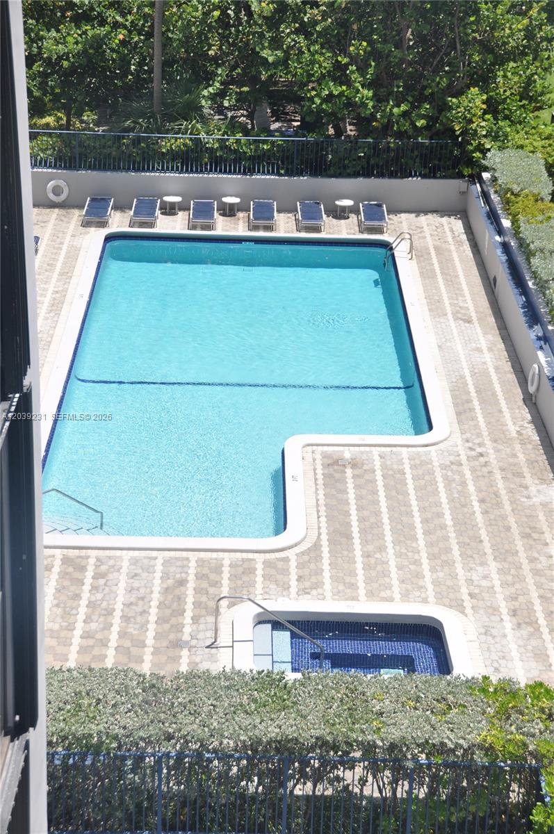 An aerial view shows a rectangular swimming pool and a small hot tub on a patio — 8877 Collins Ave # 507, Surfside FL 33154, SURFSIDE, FL