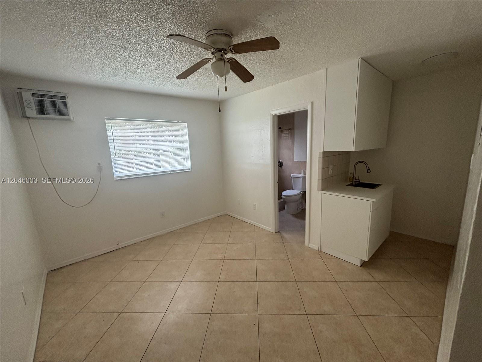 A small room features tile flooring, a ceiling fan, a window, and a kitchenette — PEMBROKE PINES, FL