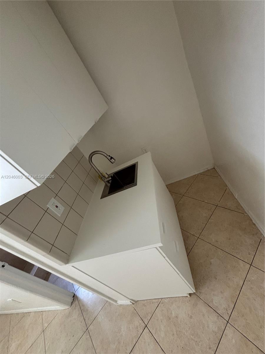 A small white kitchenette features a stainless steel sink and a tiled backsplash — PEMBROKE PINES, FL
