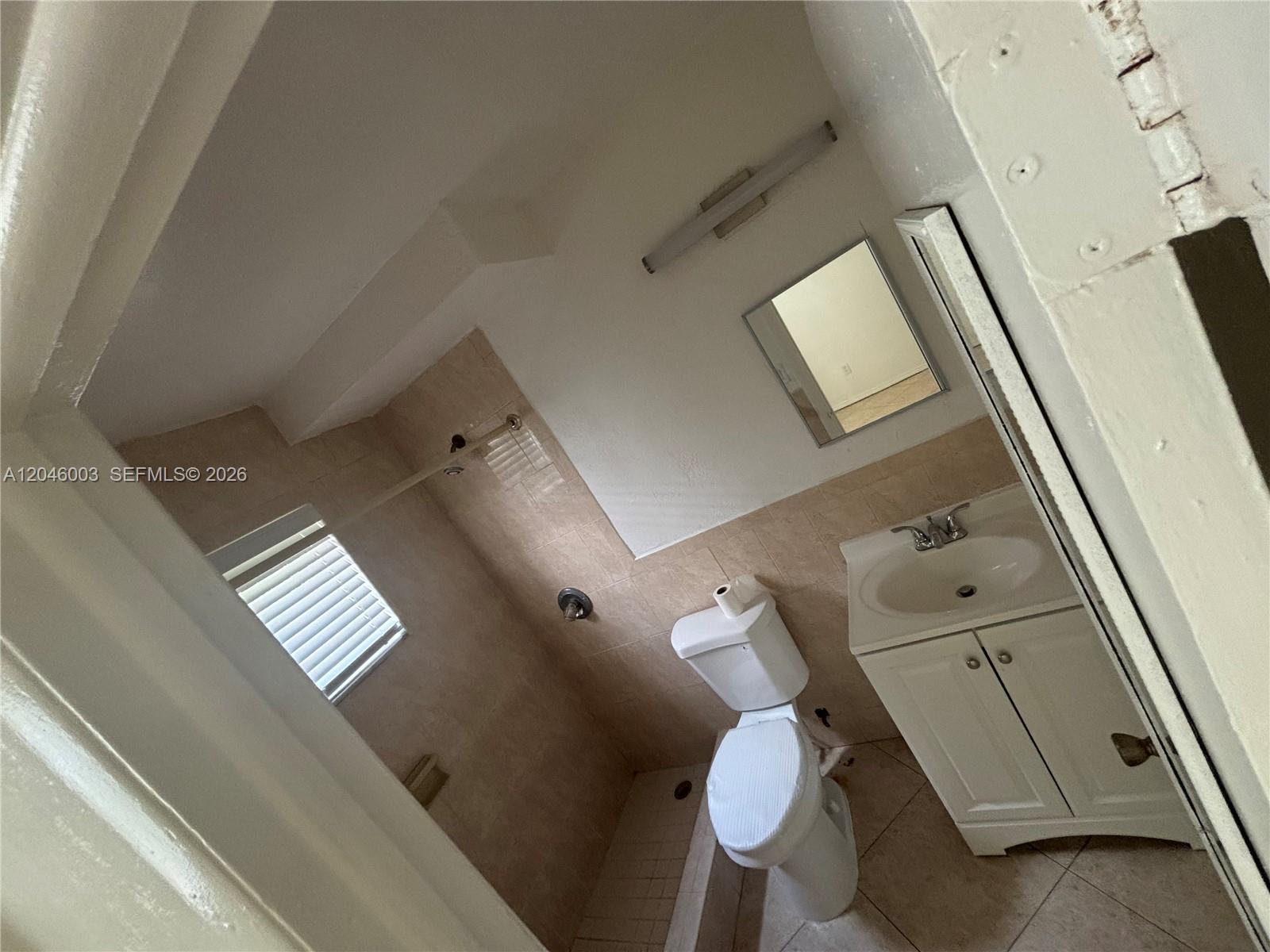 A small bathroom features a white vanity, a toilet, and a tiled shower area — PEMBROKE PINES, FL