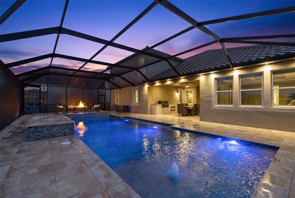 A screened-in patio features a swimming pool, hot tub, fire pit, and outdoor kitchen area — 33161 KATELAND DRIVE, WESLEY CHAPEL, FL